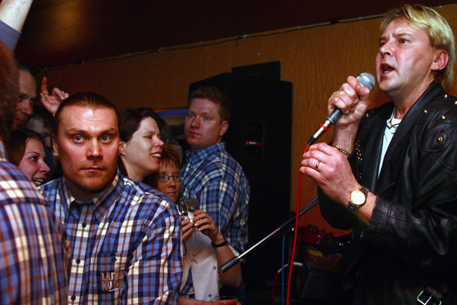 Yleisö, järjestysmiehet ja Nykänen
Sankka ruutupaitaisten järjestysmiesten rivi pitää yleisön kurissa. Kuvaaja on turvassa yhden korston takana ja pääsee kuvaamaan Matti Nykäsen samurai-showta.
Avainsanat: Matti Nykänen järjestysmies fanit ruutupaita nahkatakki samurai show